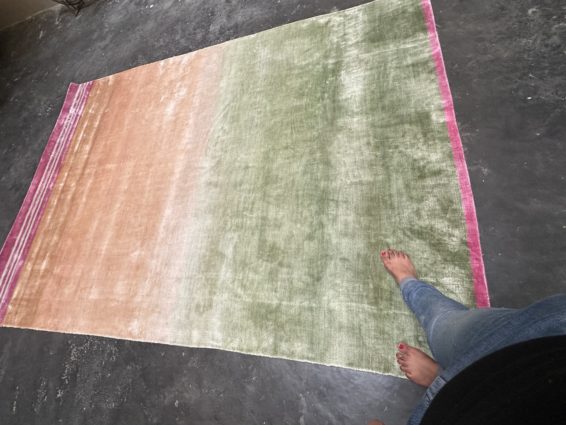 Handwoven rug with soft gradient tones of peach, green, and pink in a minimalist style